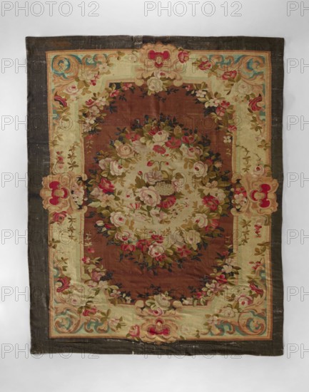 Ornamental tapestry, In the center, a bouquet of flowers surrounded by a floral wreath. Floral garlands surround the central field. Wide border with horn motifs, flowers in the corners, and floral shells. Colors: cream and light brown background; pink, red, blue, dark brown, sand, and green ornamentation. 18th/19th century, possibly France. Fabrics; height 381 cm, width 304 cm., A rectangular textile with a dark outer border and an inner decorative frame surrounds a central oval area filled with floral arrangements; the overall palette includes brown, beige, cream, pink, red, green, blue, and touches of black. The inner frame is lighter with floral sprays and ornate scroll motifs at the corners and midpoints, showing roses and leafy garlands in shades of pink, cream, and green against beige and cream backgrounds. The central oval field is a warm brown filled with a dense bouquet of flowers, featuring cream and pink roses, small red blooms, and green leaves with darker accents. The bord...