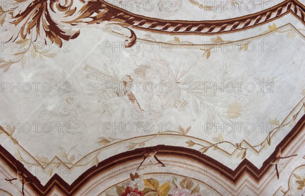 A so-called ceiling tapestry, tapestry, fabrics, tapestries, restitution provenance, fabrics, tapestries, knotted monograms, floral motifs, interior furnishings, weaving. In the center, a rosette surrounded by a floral wreath. Surrounded by rectangular frames with rounded shorter sides and floral garlands. In the corners are medallions with a knotted CKJ monogram. The border varies in color with plant patterns imitating the damask technique. Colors: pink, red, light brown, and olive. Early 19th century, France. Height 681 cm, width 385 cm., A decorative ceiling or wall surface with a pale beige background featuring ornate painted borders and floral motifs in shades of brown, tan, cream, and muted gold, with a few soft pink and faded green accents; several sweeping brown and dark brown curved bands frame the scene, and a group of stylized leaves and curling vine-like patterns in light tan and gold travel along the borders; near the center there is a faint, delicate floral arrangement re...