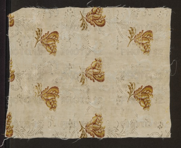Fragment of fabric, varia, fragments of silk fabrics, patterned fabrics, 18th-century silk fabric, floral patterns, fabric with preserved repeat. Weave: background in a grosgrain weave with a texture enriched by released weft threads creating a complementary ornament liseré; brocaded with colored threads. Pattern: projections of small stylized flower sprigs with large, fantastic blooms. Flowers in horizontal and vertical rows, changing direction with each row. Colors: white background ornament; white, lemon, orange, celadon, olive. Repeat: 9.5 x 16.5 cm. Date: 1740–1760. Place of origin: France. Object type: fabric. Height 29 cm, width 22.5 cm., A rectangular piece of pale beige fabric with a repeating floral embroidery motif in shades of golden yellow, brown, and muted olive, set against a background of subtle pale gray woven scrollwork; the fabric shows raw frayed edges and loose threads, and is mounted on a dark brown backing that frames it on all sides.