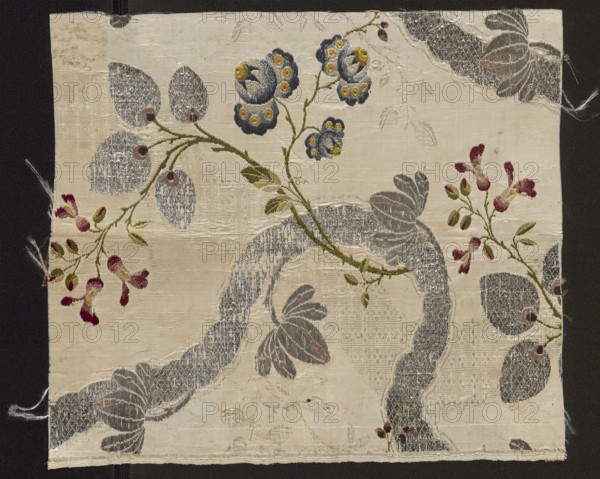 Fabric fragment, fragments of silk fabrics, patterned brocaded silk, 2nd half of the 18th century, England, fabrics with preserved selvedge, height 31 cm, width 27.5 cm. Weave structure: background - plain weave with a grosgrain liseré structure, sub-weave, brocaded. Pattern: floral motifs developing around a winding silver ribbon; fanciful flowers resembling roses and polka dots; winding lace-ribbon motif with delicate twigs entwining it. Background light-colored with liseré effect, brocaded with colorful threads and silver lamella and tightly braided silver thread. Overlay for the meandering pattern formed by tiny leafy branches and ribbons crisscrossing, ribbons brocaded with silver thread waving in the opposite direction. Brocade threads: light and dark blue, light and dark pink, yellow, white, light and dark green, two types of metallic threads, and a sorbec thread with a pink core. Colors: white background; pattern in celadon green, pink, pale blue, lemon, yellow, brown, burgundy...