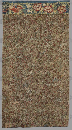 Tapestry, millefleurs, late 16th century late 1500s, Flanders. Fabric fragment; entire background strewn with motifs of small flowering plants; upper edge has a border with motifs of large flowers. Colors: black background with red, ochre, green, and yellow ornament. Height 162 cm; width 88 cm., A rectangular textile with a narrow top border featuring large floral motifs in blue, yellow, red, white, and green, and a main field densely covered with a repeating pattern of small stylized botanical motifs in muted tones of beige, olive green, red, brown, and occasional touches of pale blue and white, creating an overall textured, organic appearance.
