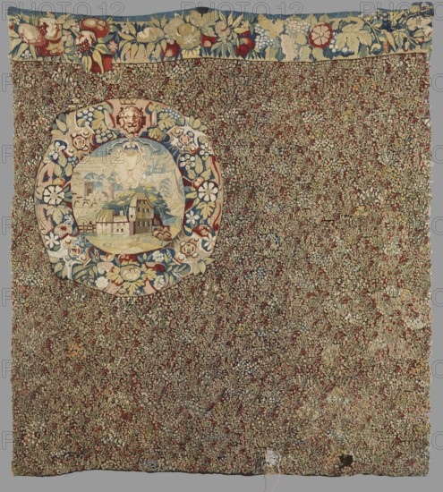 Tapestry, Fabric fragment: the entire background is densely strewn with motifs of small flowering plants. At the right edge, a medallion with an urban landscape inside; its border forms a dense wreath of flowers and grotesques. At the upper edge, a preserved fragment of a border with motifs of large flowers, fruit, and leaves. Colors: black background, red, green, blue, beige, and yellow ornamentation. Millefleurs tapestry, late 16th century, Flanders. Height 168 cm, width 154 cm., A rectangular textile with a dense floral pattern in brown, green, red, blue, cream, and yellow tones fills most of the image, with a wide horizontal floral border along the top featuring larger flower and leaf motifs in blue, red, cream, and yellow; near the upper left quadrant a circular medallion contains a small pastoral scene surrounded by a wreath-like border of stylized flowers and leaves in blue, cream, red, and yellow, and the interior of the medallion shows a cluster of small buildings and landscap...