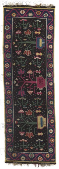 Kilim, In the center field are three bouquets—flower trees growing from low, wide vases. The outer vases are woven with the monograms SZ Cyrillic and M, and the central vase bears the date 1822. Pairs of flower sprigs are arranged between the bouquets. The entire background is filled with dots. The kilim is surrounded by a single-strip border with a floral tendril motif. Colors: black background; ornament in navy blue, red, sand-yellow, and blue-green. 1822. Poland place of origin. Fabric. Height 137 cm; width 425 cm., A long rectangular textile with a dark background framed by a colorful border in shades of blue, magenta, yellow, green, white, and red, featuring a central field filled with repeating stylized floral and geometric motifs in colors including green, pink, red, blue, yellow, and cream; the border shows interconnected diamond and flower shapes, and the ends have short fringe.