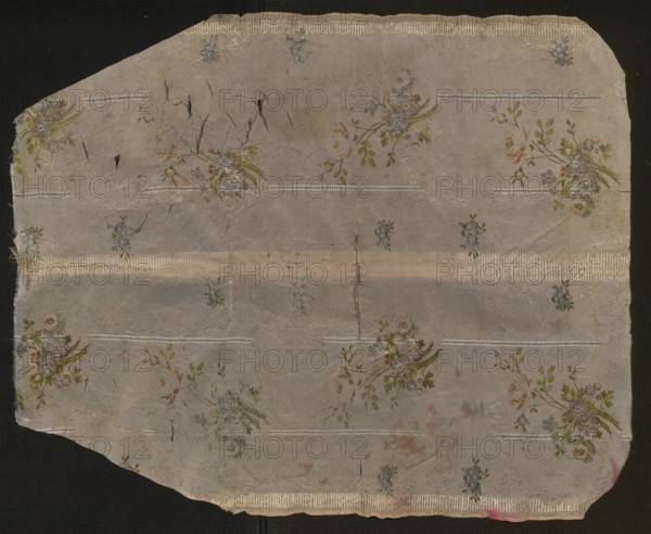 Fabric fragment, fragments of silk fabrics, patterned fabrics, fragments of a larger textile object, fragments of unsewn liturgical garments, 18th-century French silk fabrics with floral and plant patterns; Blue-pink brocaded and embroidered grosgrain. Pattern created by thicker and thinner embroidered stripes, a lace ribbon winding in the background brocaded with white weft, and larger and smaller bouquets of roses brocaded with colored wefts. Colors: pink-blue background blue and pink warp. Brocading: white, celadon, pale green, pale anguere, brownish-brown, grass green. Warp embellishments: white, blue, graphite. Sub-weft embellished with white weft. Selvedge width 0.7 cm; piece width 54 cm; pattern repeat 54 x 38.5 cm. 18th century, France. Height 67 cm, width 54 cm., A worn rectangular piece of fabric with irregular edges laid on a dark background, showing a faded pale gray-beige ground with a repeating floral pattern; several clusters of small flowers in muted greens, blues, pink...