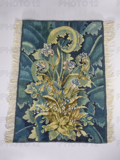 Tapestry coverings, unknown creator; repossession provenance. Design: leaves, birds, fabrics, borders, interior decorations, interior furnishings, decorative fabrics. a Seat: a bird with spread wings among large leaves and flowers; b Backrest: flowers among large leaves. Colors: green, blue, yellow, ochre, and brown. Date: 1st half of the 20th century. Place of origin: Vienna. Material: fabrics. Dimensions: height 74 cm, width 109 cm., A rectangular woven tapestry with cream fringe along the shorter edges, featuring a central botanical motif of stylized leaves and flowers in shades of green, olive, yellow, and tan, set against a background of deep teal, blue, and turquoise with swirling darker accents; several small blue and white flower clusters and pale pinkish blooms appear among the foliage, and the overall pattern includes curved shapes and layered leaf forms creating a dense, organic composition.