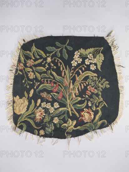 Tapestry covering, Leaves and floral ornaments; decorative fabric for interior furnishings. Design: a Seat — bouquet of lily of the valley in the center with sprigs of other flowers including tulips; b Backrest — lily flowers in the center with sprigs of other flowers including irises. Colors: dark green. Materials: fabrics. Date: 1st half of the 20th century. Place of origin: Vienna. Dimensions: height 68 cm, width 72 cm., A rectangular textile with rounded corners and fringe along the edges lies flat against a pale background; the textile has a dark background with a floral tapestry design featuring a variety of stylized flowers and leaves in colors including green, yellow, cream, red, and brown, with cream-colored fringe around the perimeter.