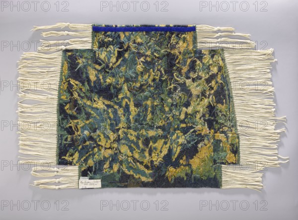 Tapestry covering, flowers, leaves, floral ornaments, fabrics, interior decorations, decorative fabrics, interior furnishings, furniture upholstery, a seat, forest landscape with a thicket of leaves; b landscape with a view of a mountain with a castle. Colors: green, blue and yellow. 1st half of the 20th century, Vienna, fabrics, height 72 cm, width 79 cm., A rectangular woven textile with an irregular stepped top and bottom edge lies flat against a pale gray background, featuring a dense, textured surface of mixed fibers in deep green, dark blue, yellow, and hints of teal with shaggy, frayed yarns creating an abstract, mottled pattern across the central field; off-white fringes extend from the left and right sides and from the stepped edges, some fringes tied into simple knots at their ends, and a narrow band of vivid blue trims the top central section of the textile.