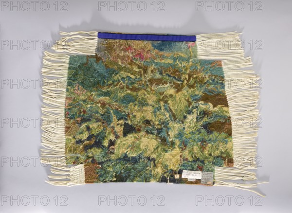 Tapestry chair cover;, repossession provenance; flowers, leaves, floral ornaments; fabrics; interior decorations and furnishings; decorative tapestries and gobelins used for furniture upholstery; 1st half of the 20th century; Vienna; height 68 cm, width 76 cm, A rectangular woven textile with long cream-colored fringe along the top, bottom, and sides, displaying a dense, textured surface of mixed yarns in shades of green, teal, olive, yellow, brown, and hints of pink and blue, with some loose, curly fibers creating a shaggy appearance; a narrow strip of deep blue fabric along the top edge; the textile rests on a pale gray background.