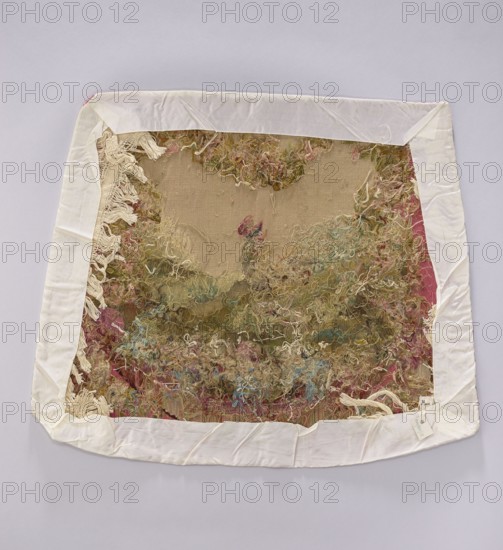 Tapestry covering, flowers, leaves, floral ornaments, roosters, boys, fabrics, interior furnishings, interior decorations, tapestries, decorative fabrics, gobelins, furniture upholstery, draperies at the bottom with flowers around. Colors: beige, light pink, sky blue, and olive green. After the mid-18th century. Possibly Beauvais or Aubusson origin. Height 56 cm, width 67 cm., An irregular square fabric piece with a white border lying flat on a pale gray background, the central area showing a textured, frayed textile with loose yarns and loops creating a tangled surface in muted tones of beige, cream, olive green, dusty pink, faded blue, and pale yellow, with some off-white fringe along one inner edge and a few areas of darker red along the outer edges; the white border has visible folds and creases and the whole piece has a slightly worn, vintage appearance.