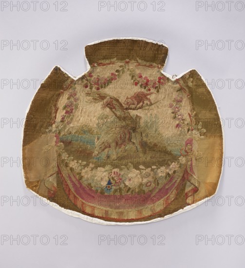 Tapestry covering, creator, unknown provenance. Floral ornaments with wildflowers and landscapes; decorative fabric for interior furnishings, draperies and furniture upholstery, featuring tapestries with flowers around the bottom. Colors: brown, tobacco, olive, pink, beige, and light blue. Dated after the mid-18th century. Possibly from Beauvais or Aubusson. Height 57 cm, width 62 cm., A worn, rounded textile with irregular protrusions at the top and sides rests on a pale background; the fabric shows a faded scene with a few animals near a fallen tree, surrounded by floral garlands and a group of flowers along the lower edge, and draped fabric forming a curved border; visible colors include tan, brown, pink, red, green, blue, and hints of cream.
