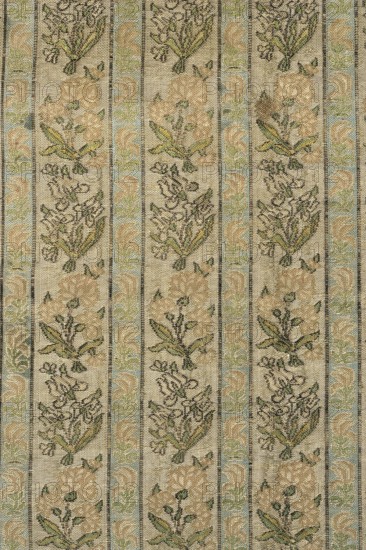 Fabric fragment. Gold-plated silk with a motif of irises and carnations in vertical stripes. Floral sprigs arranged in an alternating rhythm, turning first to the left irises and then to the right carnations. In narrower stripes, miniature stylized red flowers tulips?. Weave structure: compound weft-faced weave. Prominent wefts: gold thread with braiding, light and dark green, light and dark pink salmon, blue, white, black. Colors: gold background weft weave; patterns in green, pink-salmon, blue, black tied in weft weave. Main warp – dark yellow; main weft – cream. Dimensions of fragment: 8.0 x 4.3 cm; edge width: 0.5 cm. Selection width: 0.5 cm, fabric report: 4.3 x 8 cm. 18th century, Iran. Height 54 cm, width 28 cm., A textured vertical striped fabric with repeating floral motifs in a muted palette of beige, tan, cream, light green, pale blue, and dark olive; the design shows alternating narrow bands and wider panels, each wider panel containing stylized bouquets and leaves in beige...