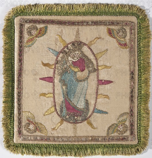 Pall, Madonna and Child iconography. Embroidery; church paraments; palls; angel heads ornament. Poland. Chalice cover made of cream satin, embroidered with colorful silk yarn, gold and silver metal thread, and sequins. In the center, in a radiant oval, Mary wearing a crown, holding the Child and a scepter, standing on a globe. In the corners are winged angel heads. Pall trimmed with narrow braid and green shreds. Flat embroidery on small thread underlays, executed with silk yarn and metal-braided threads on a silk base, decorated with silver-gold paillettes. Colorful embroidery using split and satin stitches, and gold embroidery using a laid stitch. Angels' hair is made of metal threads arranged in loops and held together with silk yarn. 18th century, Poland. Liturgical vestment, fabrics. Height 20 cm, width 19.5 cm., A square textile panel with a fringed border in shades of green surrounding an inner embroidered border in gold and muted pink, the central field in a beige or cream fabr...