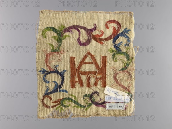 Palka?, unknown creator; church paraments; unknown origin; plant ornaments; sacred art; churches and chapels furnishings; 18th century; liturgical parament; height 21 cm; width 19.5 cm, A rectangular piece of woven fabric with a fringed bottom edge, showing a central geometric motif in a reddish-brown color and a surrounding decorative pattern of curving, vine-like shapes in green, purple, blue, pink, and red on a beige background; the fabric has areas of wear and loose threads and a few small attached paper tags that are not described in detail.