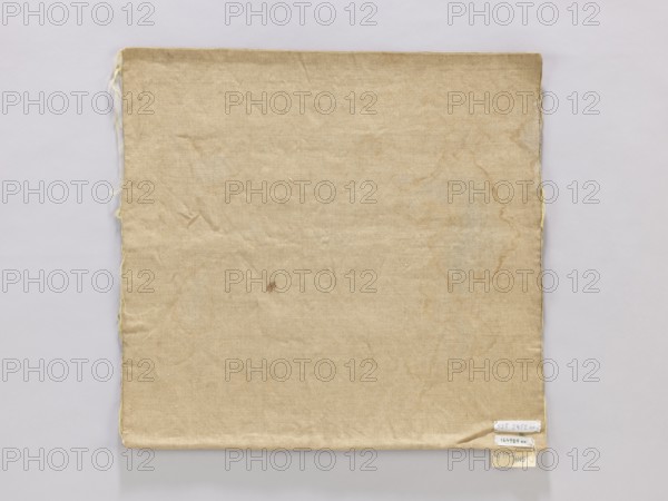 Vellum, church paraments, vellum, plant ornaments, unknown origin, 19th century, Poland, liturgical parament, height 44 cm, width 42 cm, A square piece of fabric with a worn, creased surface occupies most of the image, showing a beige to tan color with slightly darker brownish stains and discoloration in irregular patterns; the fabric has frayed edges along the left and right sides with a few loose threads visible, and the bottom right corner is slightly folded and layered over a pale background that is light gray to off-white.