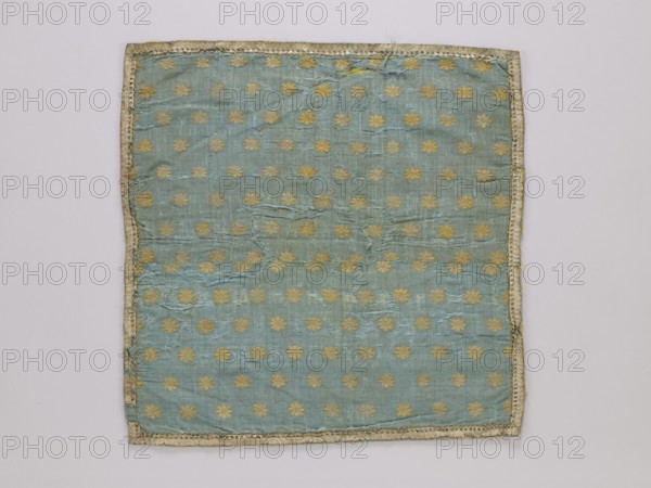 Vellum, vellum, church paraments, reclaimed provenance, 19th century, Europe, liturgical parament, height 47 cm, width 47 cm, A square piece of fabric with visible wear and fraying, predominantly light blue with a repeating pattern of small floral motifs in a gold tone, bordered by a narrow trim in a pale off-white or beige color, with areas of threadbare texture and slight discoloration in places.