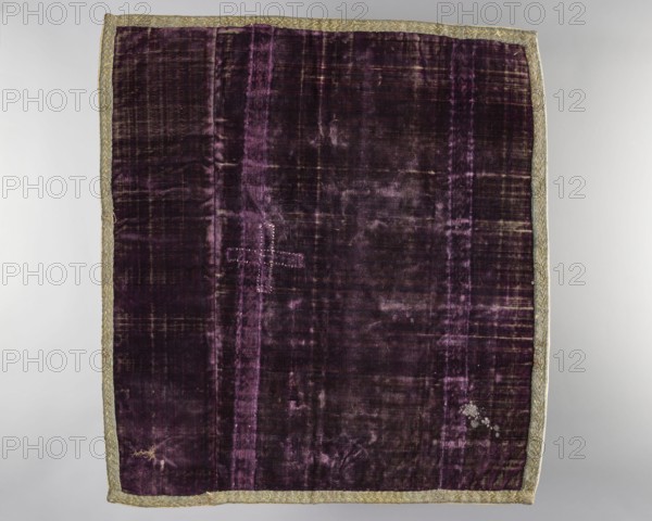 Velum;, church paraments; revindication provenance; flowers; plant ornaments; sacred art; churches and chapels furnishings; 18th century, Italy; liturgical parament; height 46 cm; width 51 cm, A rectangular textile laid flat with a deep purple velvet field showing areas of lighter purple sheen and worn darker patches, bordered all around by a narrow metallic trim in a muted gold-green tone; the velvet surface has visible vertical banding and a few irregular worn spots, including one area with a pale cluster of abrasion and another small rubbed area, and there is a stitched cross-shaped repair in a slightly lighter purple thread near the upper left quadrant.