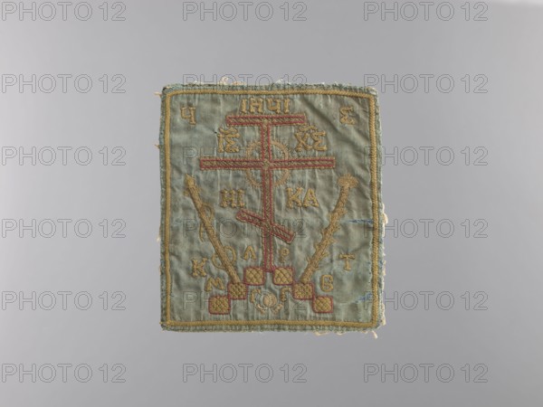Palka, unknown,  ; church paraments, crosses, plant ornaments, sacred art, churches and chapels equipment; Bukowina; liturgical parament; height 15.5 cm, width 14 cm, A rectangular embroidered cloth panel with a faded blue-green background and a gold border, showing a central vertical cross motif outlined in red and gold thread, flanked by two diagonal staffs embroidered in gold; the design includes decorative gold stitching and small checked red and gold squares near the lower center, with additional small embroidered marks around the central motif; the edges of the textile appear slightly frayed and the overall colors visible are blue-green, gold, red, and touches of beige.