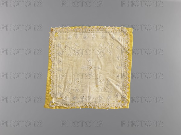 Pall, church paraments, provenance, white pall made of linen, embroidered with white cotton thread. Equal-armed cross in the center, stylized flowers in the corners, small flowers around the edges. Trimmed with bobbin lace with serrations. Lined with yellow silk. 18th century, Poland; liturgical parament; height 16 cm, width 15 cm., A square cloth with a pale cream central panel featuring embroidered floral and leafy motifs and a decorative crocheted lace border, set against a bright yellow fabric backing that peeks out around the edges; visible colors include cream, yellow, and shades of gray in the background.