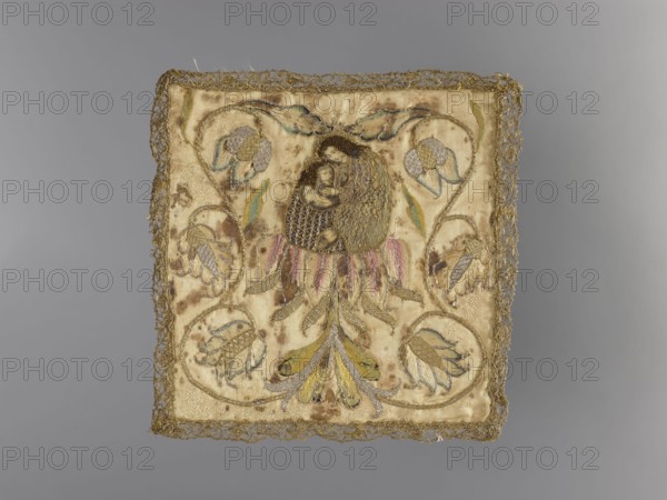 Embroidered pall, 18th century, Poland, liturgical vestment. Pall of cream-colored silk satin, embroidered. In the center, Mary and Child on a flower of an imperial checkerboard, from which grows a floral tendril encircling the figures. Edges trimmed with narrow gold bobbin lace. Embroidery executed with laid stitch using metal threads a plate braided on a silk yarn and in the figures' hair a wire densely wrapped in silk, held with silk yarn and split stitch using silk threads. Iconography: Madonna and Child; motifs: flowers, leaves, plant ornaments. Height 18 cm, width 18 cm., A square textile with a decorative border sits against a gray background; the fabric is primarily cream and beige with visible brown stains and spots, and it features embroidered floral motifs in shades of gold, yellow, pale green, pale blue, and muted pink; a central embroidered oval contains a small dark-toned portrait-like image surrounded by gold and brown threadwork, and a group of petal and leaf shapes in ...
