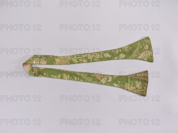 Stole made of Lyon material; maker, early 18th century, Lyon, France; liturgical vestment for church use; decorated with flowers, leaves, and plant ornaments; dimensions: length 158 cm, width 16 at narrowest / 7 cm unclear, A long, narrow fabric strip with a floral woven pattern lies flat on a pale background, forming a loose loop at one end and two tapered ends at the other, showing a green base color with accents of gold, light pink, and cream in the decorative motifs.