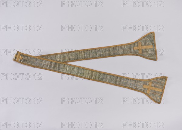 Stole, church paraments, flowers, leaves, liturgical vestments, plant ornaments, sacred art, churches and chapels furnishings, 18th century, liturgical vestments, length 196 cm, width 20 7 cm, A long fabric band with a muted greenish-blue woven pattern and gold trim runs diagonally across a pale gray background, forming a gentle zigzag; both ends widen into triangular flares edged in gold and each flare bears a gold cross-like applique; the band shows subtle sheen and faint linear stitching, with overall colors of greenish-blue, gold, and pale gray.
