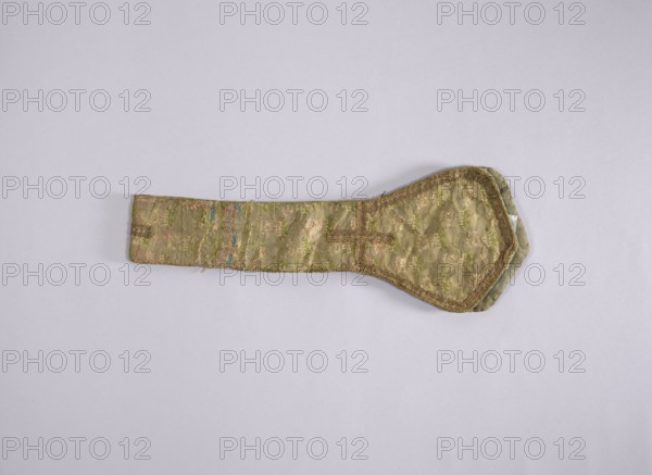 church paraments; flowers, leaves; liturgical vestments; plant ornaments; sacred art; churches and chapels furnishings; 18th century; France; liturgical vestments; length 81 cm; width 14 cm, A flat fabric object with a long narrow rectangular section attached to a wider rounded end, lying on a light gray background; the fabric shows a patterned texture with woven floral-like motifs and trimmed edges, and visible wear and fraying in places; colors visible include shades of green, muted gold, beige, pale pink, and hints of blue.