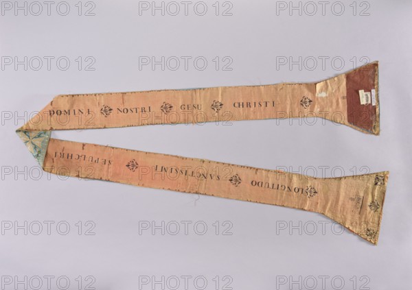 Stole, Stole made of blue satin, embroidered with a floral tendril motif. In the center of each paddle and on the center waistband are embroidered equal-armed gold crosses. Pink silk lining with the printed inscription LONGITUDO SANCTISSIMI SEPULCHRI DOMINI NOSTRI GESU CHRISTI, stylized flower bushes, and representations of architecture temple in Jerusalem?. A card is attached to the stole with ink text describing it as a stole of the Tomb of Christ in Jerusalem on blue satin, embroidered with flowers, pink lining with the inscription, sent by the Latin Patriarch in Jerusalem in 1828 to Fr. Tomasz de Nowina Nowin. Note: Latin Patriarch at that time was Francesco Maria Fenzi 1738–1829. Tomasz Nowinski 1746–1830, last General of the Order of the Holy Sepulcher in Poland, 18th/19th century. Liturgical vestment; length 242 cm, width 11.5 cm., A long, narrow fabric sash laid flat against a pale gray background, showing two tapered ends with triangular pieces and a wider rectangular midsecti...