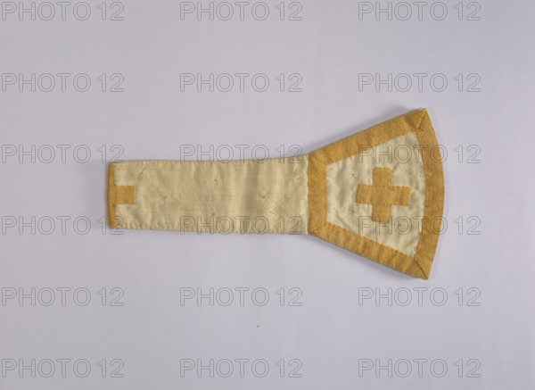 church paraments, liturgical vestments, sacred art, churches and chapels equipment. 18th century, Poland. Liturgical vestment chasuble, height 83 cm, width 21 cm. Description notes liturgical embroidery, its form, symbolism, execution techniques, significance in Polish religious tradition, and the role of religious orders Warsaw Capuchins in shaping liturgical culture; includes analysis of theological content, aesthetic value, and embroidery techniques., A fabric object lies flat on a pale background, showing a long rectangular strip attached to a wider trapezoidal end. The fabric appears in shades of cream and golden yellow, with the central strip mostly cream and the edges and trim in golden yellow. The wider end has a golden yellow border and a golden yellow cross-like shape sewn into the cream center, and there are visible stitch marks and small thread details across the surface. The background is a very light grayish white, and the overall scene is evenly lit.
