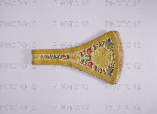 Maniple, 18th century, Poland. Liturgical vestment made of woolen fabric, length 74 cm, width 22 cm. Embroidered along the edges with floral tendrils. Equal-armed crosses embroidered at the ends of the paddles in the center. A floral rosette motif embroidered where the paddles merge into the maniple's belt. Around the edges is an embroidered band with a carp scale motif imitating gold braid. Predominant colors: white background with yellow, green, red, and blue ornamentation. Church paraments; sacred art; churches and chapels furnishings., A fabric object with a tapered shape lying flat on a pale background, primarily in shades of yellow and cream with embroidered floral decoration in red, pink, blue, green, and purple, featuring a woven yellow border and a central embroidered motif in yellow surrounded by a ring of colorful flowers and green leaves, with the edges showing a slightly darker beige or tan fabric and the overall surface displaying stitched texture and gentle creases.