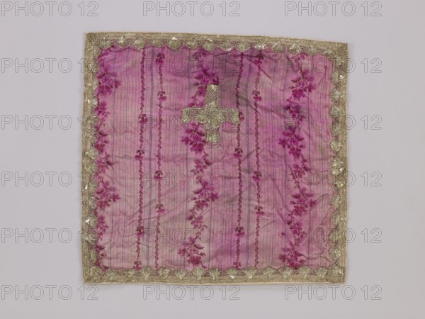 Velum, vellum, church paraments, 18th/19th century, France, liturgical parament, height 44 cm, width 46 cm, A square fabric panel in shades of pink and magenta with a faint striped background and floral motifs, edged with a scalloped metallic trim in a gold color; near the center is a small cross-shaped patch made of the same metallic gold material; the fabric shows subtle wrinkles and areas of slightly darker and lighter pink, with floral patterns in deeper magenta and purple tones throughout, all set against a pale neutral background.
