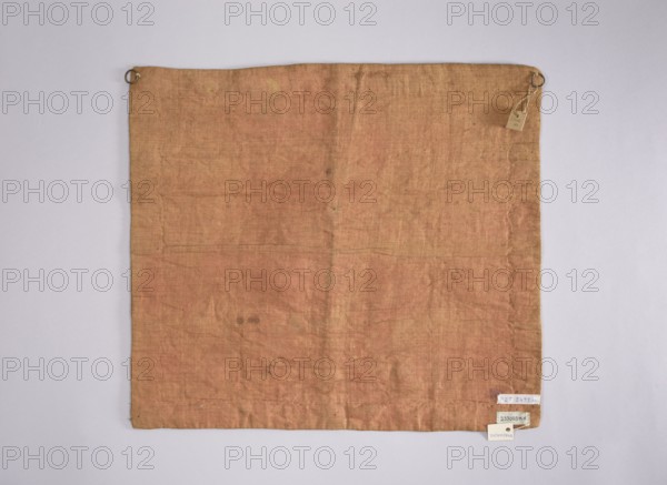 Velum; creator, Rómmel, Jadwiga donor; ; church paraments; flowers, leaves, plant ornaments; sacred art; churches and chapels furnishings; 2nd half of the 18th century; France; liturgical parament; height 47 cm; width 53 cm, A square piece of fabric laid flat against a pale gray background, the fabric showing a faded, dusty pinkish-orange color with variations in tone and some subtle darker spots and faint discolorations; the fabric has visible weave texture and creases forming soft vertical and horizontal lines, with slightly irregular edges and a few small frayed areas; metal rings are attached near the top corners with a small hanging tag near one ring, and a few small paper tags affixed near one lower corner; overall colors visible include dusty pinkish-orange on the fabric, pale gray in the background, and small accents of metallic gray and off-white on the rings and tags.