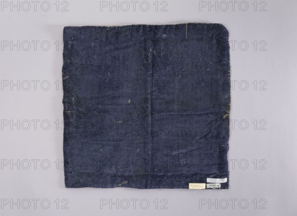 Velum;, church paraments; revindication provenance; flowers, leaves, plant ornaments; sacred art; churches and chapels furnishings; 18th century, France; liturgical parament; height 47 cm, width 47 cm, A square piece of fabric laid flat on a pale background, showing a dark blue textile with visible wear and small areas of discoloration and fraying along the edges, a subtle embossed or stitched floral and scrolling pattern across its surface, faint crease lines where the fabric has been folded, and a few small light-colored spots and flecks near the edges.
