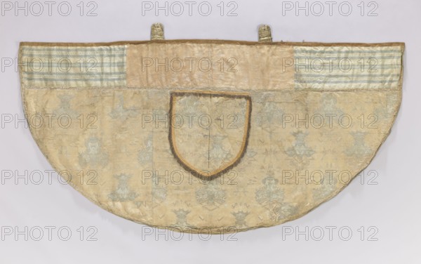 Church cope of silver brocade with Chinese motifs. Pretext sewn from two Polish fabrics—cream satin with a floral pattern and sky blue with blue stripes—trimmed with galloon. Hood trimmed with fringe; silver buckle with a carp scale motif. Skirt made of silk fabric with a blue silk weft and embellished with metal thread and silk yarn. Background shows a satin warp pattern with liseré decoration lampas. Motifs symmetrically composed of large fanciful vases with Chinese figures topped by Chinese-style buildings forming a chalice; between them are birds and elements of Chinese architecture. Pattern includes elements reminiscent of lace designs. Metal brocade thread on a loosely braided, crimped white silk core; brooch threads: braided metal thread and orange, blue, white, and yellow silk yarn. Height 51 x width approx. 77 cm. Church cope of silk with Chinese motifs France, early 18th century. Silk fabric for the skirt of a cope—early 18th century; liturgical vestment, length 128 cm, width...
