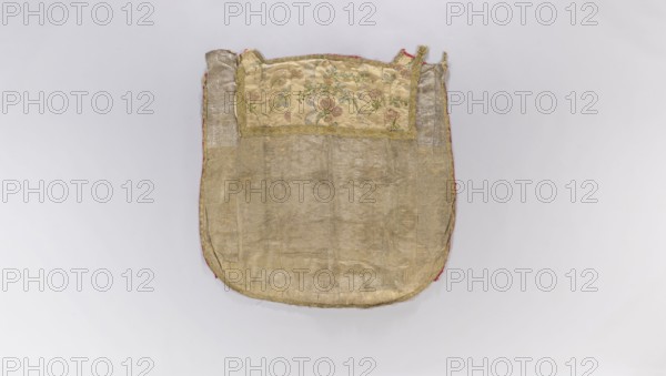 Church cope, church copes; liturgical vestment decorated with flowers, leaves and plant ornaments; church paraments; sacred art; furnishings for churches and chapels; 18th century, France; height 140 cm, width 136 cm., An oval-shaped textile item lies flat on a pale background, showing a worn central panel of dull gold and beige fabric with a slightly shiny, textured surface and visible seams; the top section features a rectangular inset of lighter cream fabric with a floral embroidered pattern in green, pink, and muted red tones framed by gold trim; the outer edges reveal a narrow border of faded red and small areas of darker gold trim, and the overall piece displays creases, fraying, and subtle variations of beige, gold, cream, green, pink, red, and muted brown.