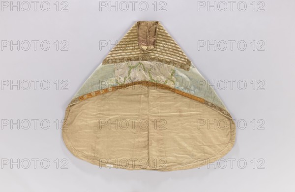 Church cope, unknown origin, decorated with flowers and leaves, plant ornaments; liturgical vestment for church use; sacred art; used in churches and chapels furnishings; 18th century, France; height 133 cm, width 149 cm, An item with a triangular top and rounded lower edge lays flat against a pale background; the upper triangular section has striped fabric in muted gold and cream, flanked by textured gold trim, below which are panels of faded green, blue, and beige fabric with subtle floral and vine patterns, separated from the lower section by a narrow band of orange-gold trim; the large rounded lower area is made of plain beige fabric with visible seams and slight creases, and the overall color palette includes beige, gold, cream, green, blue, and orange-gold.