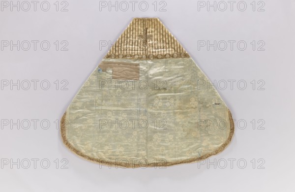 Church cope, unknown origin, flowers, leaves, liturgical vestment with plant ornament, church parament for churches and chapels, 18th century, France; height 133 cm, width 149 cm, A fabric garment with a triangular upper section and a rounded lower edge lies flat against a pale background; the top section features vertical stripes and a decorative trim in shades of gold and beige, while the larger lower panel is a muted pale green with a subtle floral pattern and areas showing discoloration and patched fabric in beige and tan; the outer edge is finished with a gold-toned trim, and there are small blue thread marks and faint wrinkles visible across the surface.