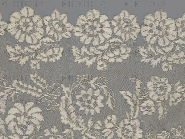 Shawl, shawl; purchase provenance; clothing accessories; women's clothing; fashion; lace; serrated edges; in their bends twigs with two flowers; in the middle part curling flower twigs; 19th century, Europe; length 48 cm; width 260 cm, A close-up of delicate lace fabric showing a repeating floral pattern with large and small stylized flowers, leafy sprigs, and winding stems embroidered onto a fine hexagonal net background; the embroidered motifs are an off-white or cream color with slight fraying at some edges, and the net background appears gray, creating contrast between the cream embroidery and the gray mesh.