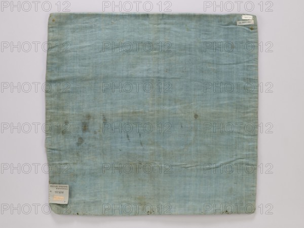 Velum - fragment; unknown creator; churches and chapels equipment; church paraments; liturgical parament; fabric; 18th century, France; height 52 cm, width 54 cm, A square piece of fabric laid flat against a pale background, predominantly light blue with areas of faded blue-green and faint grayish discoloration; the fabric shows a woven texture and slight horizontal and vertical creases, with a few small darker stains and spots scattered across the surface, a few tiny darker marks along the bottom edge, and a small folded corner at the lower left.