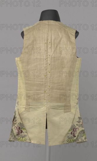 Vest, Repossession provenance. Floral and plant ornaments, patterned brocaded silk fabric. Predominant ornamental colors: silver, plum, green, and raspberry. Front of brocaded silk fabric with motifs arranged around the edges. Fastened with 12 buttons embroidered with gold threads. No collar. Side flaps with flapped pockets, three buttons under the flaps as for the closure. Back: bottom and sides of fabric as on the front, but the cut-out pieces are plain without brocade. Cream silk lining. 1740–1760, England fabric possibly, Silesia. Garment; length 74 cm., A sleeveless garment displayed on a black mannequin back with a neutral gray background, made of a light beige fabric overall with paler cream side panels and lower sections; the back center seam shows small round fastenings and stitching details; the lower back splits into two panels revealing triangular lining pieces with floral woven fabric in shades of green, purple, pink, and muted gray; the garment shows subtle variations in ...