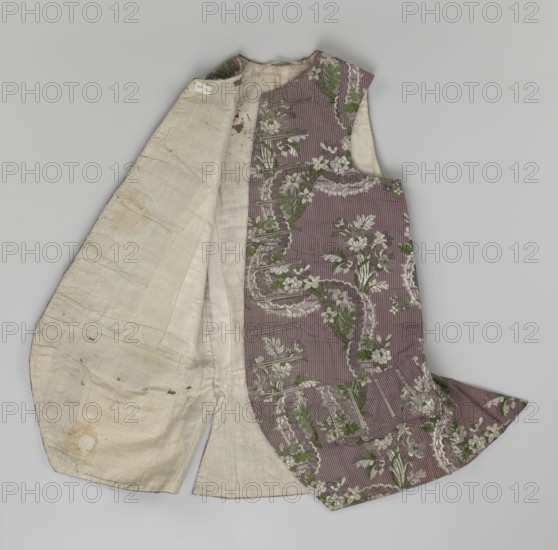 Vest, floral ornaments, patterned fabrics, Henryków German: Heinrichau - place of repository, fastened at the neck with 11 buttons; flaps on the sides with 4 buttons below them for fastening; embroidered in gold; back made of brown canvas at the top and fabric at the bottom as on the front; 1750s, Silesia; garment; length 76 cm., A sleeveless garment laid flat showing an outer patterned fabric and a plain inner lining. The outer fabric is a muted purple with a floral and decorative stripe pattern in shades of green, white, and a darker muted tone, forming repeating motifs and scalloped shapes. The inner lining is a light beige to off-white with visible creases, slight stains, and areas of wear. The garment has a rounded neckline and a curved hem detail, with seams and stitching visible where the lining meets the patterned outer fabric. The overall colors visible are purple, green, white, beige, and small areas of brownish discoloration.