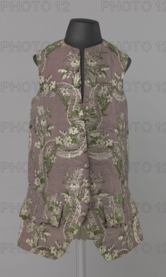 Vest, floral ornaments, patterned fabrics, Henryków German: Heinrichau - museum repository, fastened to the neck with 11 buttons. Flaps on the sides, below them 4 buttons as for the fastening, embroidered in gold. The back is made of brown canvas at the top and fabric at the bottom as on the front. 1750s, Silesia, garment, length 76 cm, A sleeveless, knee-length garment displayed on a black mannequin torso, made of a ribbed fabric in a muted mauve color with an all-over floral brocade in shades of green and off-white; the front has a narrow standing neckline and a vertical row of fabric-covered buttons and decorative loops, with a short pleated peplum and flap pockets near the hem, and the floral pattern forms scalloped borders and clusters of leaves and blossoms against the mauve ground.