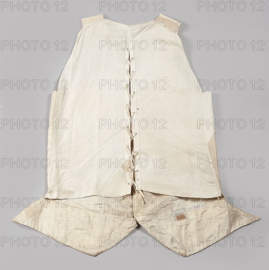 Vest, floral ornaments, geometric ornaments. Fastened to the neck with 9 covered and embroidered buttons. Side flaps with pockets underneath. Laced canvas back. 2nd half of the 18th century, Poland. Garment; length 74 cm., A flat, sleeveless garment laid out against a gray background, made of off-white and beige fabric with a central vertical seam held by a series of narrow fabric ties, a few small stains and darker smudges visible on the surface, shoulder straps of slightly darker beige, side panels creating a subtle taper, and two pointed lower flaps that extend outward with creases and worn areas.