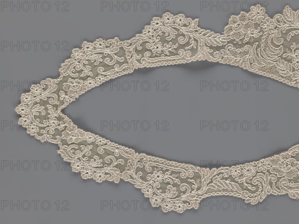 Collar, origin unknown, floral ornaments, clothing accessory for women's clothing, fashion, embroidery. Connected at the bottom by a wide, irregular inset. 2nd half of the 19th century, Europe. Width 19 cm, length 50 cm., A delicate lace trim with floral and scrollwork patterns arranged in an oval shape against a flat background; the lace appears in an off-white or cream color with intricate openwork featuring small flowers, swirling motifs, and scalloped edges, while the background is a muted gray.