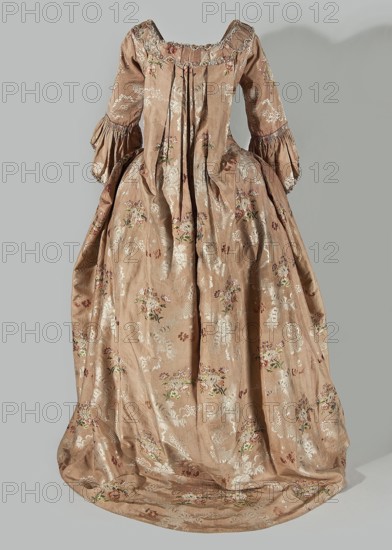 Robe à la française dress, floral ornaments, ribbon, flower bouquets, robe à la française clothing, ruffles, clothing, women's clothing, women's fashion, dresses, patterned fabrics, 18th century clothing. Two-piece dress made of silk in the colour of dried rose with motifs of colourful flower bouquets and winding ribbons of white lace. The overskirt manteau is open at the front, with a triple pleat extending almost the entire width of the back, flowing into a train. The bodice is on a linen lace with boning, laced at the front. The neckline is deep and square. Narrow elbow-length set-in sleeves trimmed with ruffles of the same fabric. Neckline and bodice edges trimmed with a pleated ruffle, decorated with multicolored cord trimmings twisted into tiny flowers. No lining. The skirt is gathered with symmetrical pleats, spread out to the sides. Fabric report: height 24.5 cm, width 48.5 cm; width of fabric piece: 54 cm. Date: 1760–1765. Place associated: Silesia; possible origin: France. Cl...