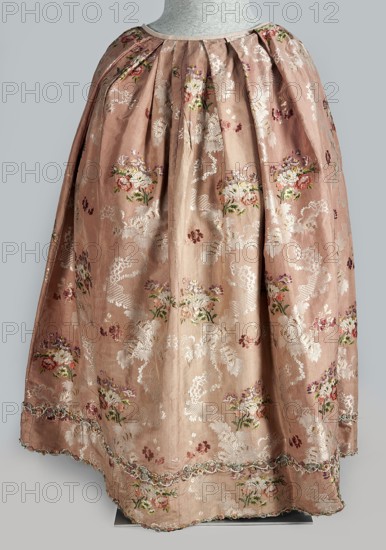 Robe à la française dress, floral ornaments, ribbon, flower bouquets, robe à la française, ruffles, women's clothing, women's fashion, patterned fabrics, 18th century clothing. Two-piece silk dress in the colour of dried rose with motifs of colourful flower bouquets and winding ribbons of white lace. Overskirt manteau open at the front, with a triple pleat extending almost the entire width of the back, flowing into a train. Bodice on linen lace with boning, laced at the front. Deep square neckline. Narrow, elbow-length set-in sleeves trimmed with ruffles of the same fabric. Neckline and bodice edges trimmed with a pleated ruffle decorated with multicoloured cord trimmings twisted into tiny flowers. No lining. Skirt gathered with symmetrical pleats, spread out to the sides. Fabric report: height 24.5 cm, width 48.5 cm; width of fabric piece: 54 cm. Date: 1760–1765. Place associated: Silesia; possible origin: France. Clothing length 158 cm., A garment displayed on a mannequin torso with ...