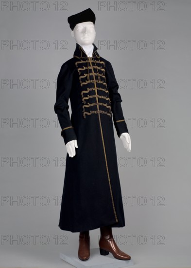 Taratatka, Polish men's garment, national costume, late 18th century, Poland. Fitted at the top, flared at the bottom; fastened at the front with loops and pegs incorporated into decorative braiding. High stand-up collar tied with a string finished with tassels. Long set-in sleeves with rolled-up cuffs. Back cut with a central panel of fabric, widened from the waist on the sides by semi-flared pleats. Side-seam pockets. Edges of the half-length skirt, collar, back pleats, and sleeve seams edged with brown silk ribbon. Hem on the back folds finished with rosettes and small tassels. Materials: wool navy-blue cloth, silk trimmings; skirts lined with blue plain silk; upper part lined with brown wool. Hand-sewn. Length 128 cm; bottom circumference 312 cm., A mannequin dressed in a long dark coat with decorative trim and frogging across the front, wearing a matching dark cap and a white high collar, with visible white hands and brown heeled boots against a plain light gray background; colors...