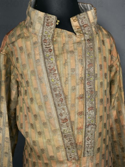 Zupan from the uniform of the Order of St. Stanislaus. Zupan made of pink and crimson Grodno fabric with stripes and a small floral pattern, long. Fitted at the top, slightly flared at the bottom. Fastened at the front to the neck with haberdashery buttons. High, stand-up collar, adjustable at the back with a buttoned flap. Long, set-in sleeves with turn-up cuffs fastened with hooks. Around the fastener, on the sleeve seams and cuffs, gold-leaf galloon with floral sprigs and baskets. Back of crimson satin, cut with a central column of fabric like a kontusz, widened from the waist on the sides by semi-flared pleats, adjustable at the top with ribbons. Back and lining of white silk satin. Hand-sewn. Zupana fabric; crimson silk grosgrain brocaded with braided gold thread and silk wefts. Gold stripes on a crimson background and miniature sprigs of stylized flowers. Poland, Grodno, 1780s. Gold galloon with a fine floral pattern. Fabric report: sample 5 x 4.5 cm, fabric length 55.5 cm, fabri...