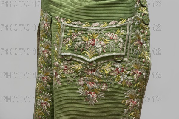 Habit à la française, repossession provenance; floral and plant motifs; fashion, men's clothing; embroidery; 18th century clothing. Green silk habit embroidered with small bouquets of flowers. Fitted at the top, widened at the back from the waist down with two slit pleats. Fastens at the front with hooks and eyes. Semicircularly cut lapels overlap at breast level and are cut off at the bottom. High standing collar. Long sleeves set in at elbow height, cut in an arc, finished with wide slightly protruding cuffs. Side pockets at hip level covered with trapezoidal flaps. Back cut with a center seam; slits at hip level; center back flaps meet without a pleat. Embroidery in a wide band around edges, cuffs, pockets, collar, and back pleats. Decorative buttons sewn in threes on cuffs, under pocket flaps, two at top of back pleats, and in the pressed pleats. 1770s, Silesia; made in France. Garment; length 112 cm., A section of a green ribbed fabric panel decorated with ornate floral embroidery...