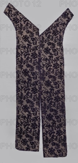 Fabric fragment, textiles, fragments of silk fabric, patterned fabric with plant motifs; cochineal and indigo dyes; fragment of a larger textile object. Patterned, looped purple velvet with plant motifs. Motif: plant tendril of small fanciful floral twigs in asymmetrical arrangements creating a net pattern. Weave construction: grosgrain background with silk bold and linen weft in natural color, purple silk warp; looped silk purple cover. Dense plant composition of finely curved twigs with varied leaves and flowers—delicate, refined, segmented pattern. Arranged in rows with a half-report shift; calyx of dominant flower alternately tilted left or right in the rows. Design repeat report length 24.7 cm × width 13.2 cm. 17th century, Italy. Fabric dimensions: height 110 cm, width 18 cm., A long fabric garment shaped with a deep V neckline and two wide straps, laid flat against a light gray background, showing a repeated ornate floral and scroll pattern in dark purple on a pale grayish-beige...