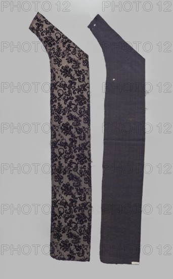 Fabric fragment, fragments of silk patterned fabric, patterned purple looped velvet with plant motifs. Plant tendril made of small fanciful floral twigs in asymmetrical arrangements creating a net pattern. Weave construction: grosgrain background with silk and linen weft in a natural color, purple silk warp; looped silk purple cover. Dense plant composition, finely curved twigs with a variety of leaves and flowers, arranged in rows with a half-report shift and with the calyx of the dominant flower tilted alternately left or right. Design report length 24.7 x width 13.2 cm. Maker: Justyna Boninska, 17th century, Italy. Fabric dimensions: height 110 cm, width 18 cm. Materials/dyes noted: silk, linen; cochineal and indigo dyes., A vertical image shows two long fabric pieces side by side against a pale gray background. The left piece has a beige base with an intricate dark purple floral damask pattern running across its length and a slightly curved upper end. The right piece is a solid dee...